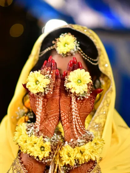 A classic bridal pose showing off the stunning henna stain. The colour is so vibrant against the yellow flowers.
