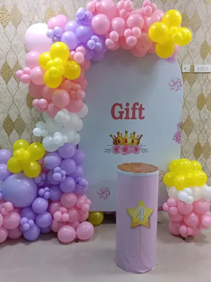 A princess-themed setup for a 4th birthday. This decoration features a custom arch backdrop and a colorful balloon arrangement in pastel pink, purple, and yellow.