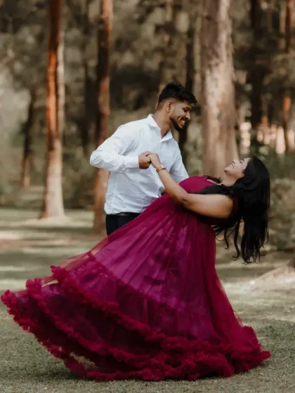 We help create joyful, candid moments with outfits that move with you. This couple is captured in a playful dance, with the tiered magenta gown adding a splash of color and life to their forest photoshoot.