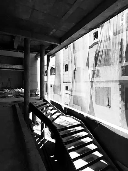 Sunlight streams through the treads of an unfinished staircase, highlighting the raw structure and the play of light we consider even in the earliest stages.