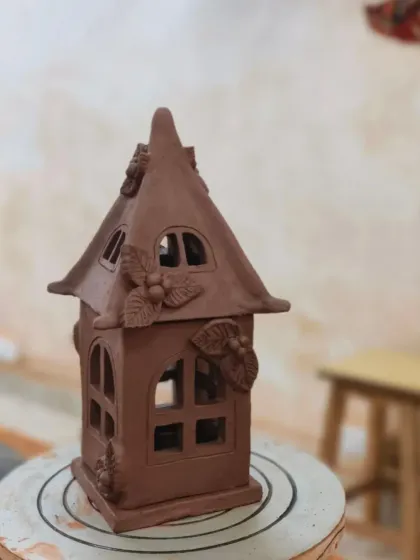 This unglazed clay house lantern is ready for the kiln. The structure is built by hand using slab techniques, and the details are carefully sculpted and attached before firing.