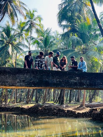 A group of friends posing on a coconut log bridge in the backwaters of Honnavara.
