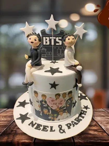 A special cake for fans of the K-pop group BTS. This design features fondant figures of the band members, star decorations, and an edible image of the group, personalized for two fans.