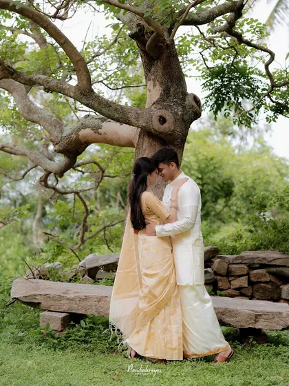 A couple shares an embrace under a sprawling tree, creating a naturally framed romantic portrait.