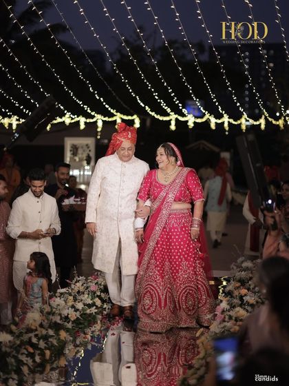 The bride's entrance down the mirrored aisle, walking towards the groom under a canopy of twinkling lights.
