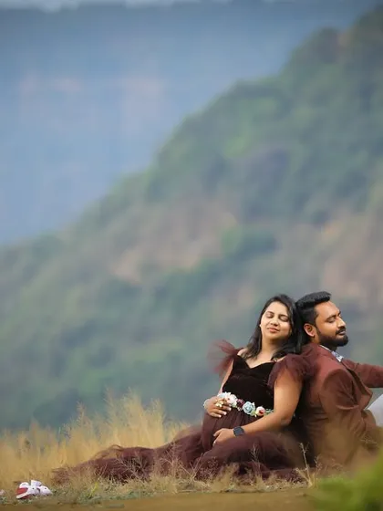 A peaceful moment for an expecting couple in the mountains. The dark, voluminous gown spreads around them, adding to the romantic and serene feel of the photo.