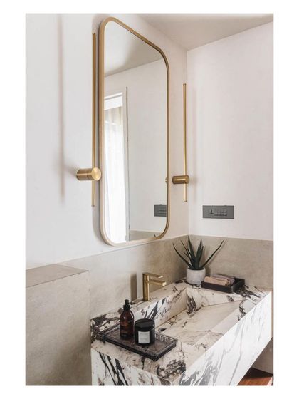 In this powder room, a monolithic marble vanity creates a bold statement. The dramatic veining of the stone is complemented by a simple, elegant brass mirror and fixtures.