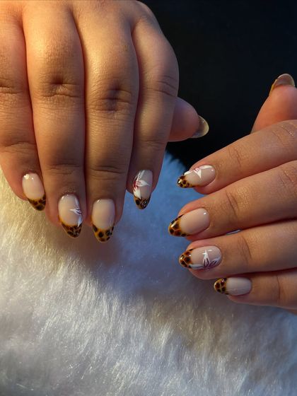A chic and trendy animal print design. We created a tortoise shell French tip and added delicate, hand-painted white floral accents for a beautiful contrast.