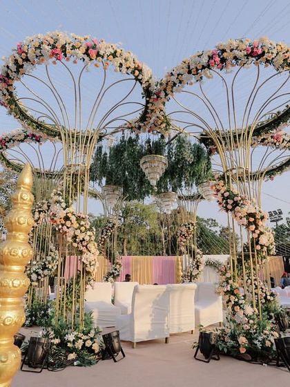 A side view of the grand pastel mandap, highlighting the golden pillars, traditional finials, and the sheer scale of the floral arrangements.