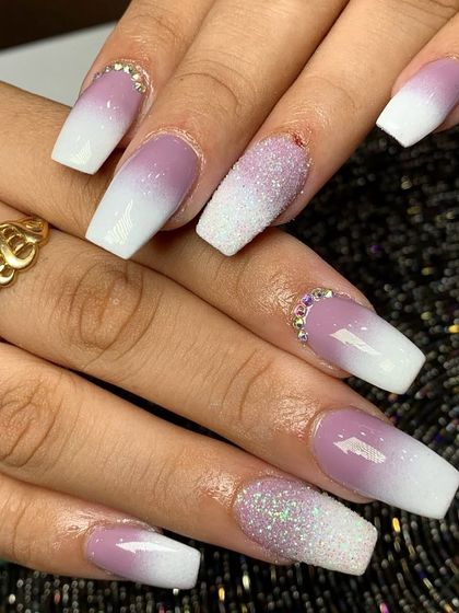 A beautiful purple and white ombre set on coffin nails, with sugar glitter accents and rhinestones.