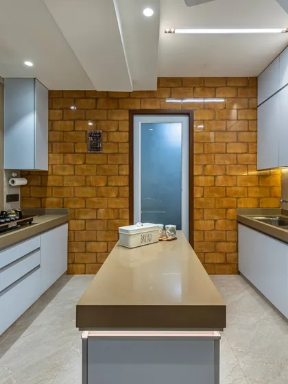 This contemporary kitchen from the Filigree House project features an industrial-inspired brick wall. The light blue cabinets and beige island countertop create a modern palette that is both stylish and functional.