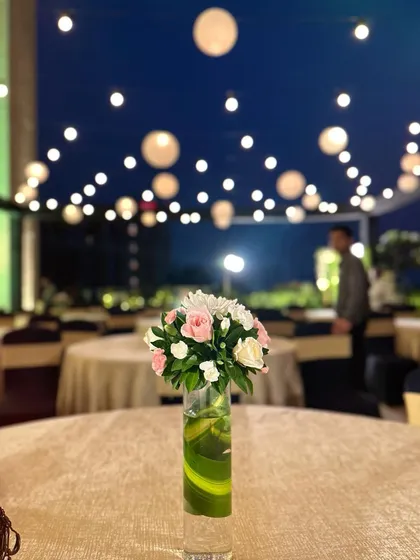 A simple yet elegant table centerpiece for an evening event. The background shows the ambiance created with hanging paper lanterns over the guest seating area.