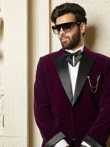 A closer look at the wine velvet tuxedo, focusing on the rich fabric and the sharp contrast of the black satin lapel. This is a garment designed to be seen and admired.