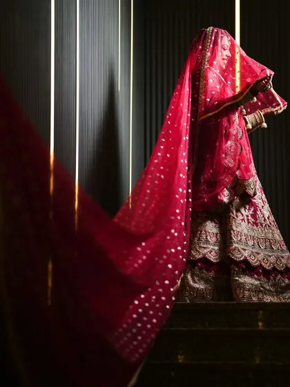A dramatic shot of the bride, with her long red veil creating a beautiful silhouette.