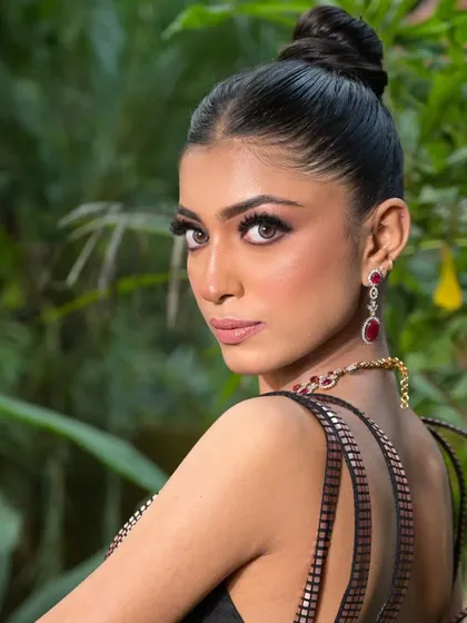 An over-the-shoulder pose that highlights the clean silhouette of the updo against the lush, green background of the shoot location.