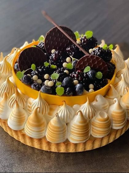 A stunning Blackberry Meringue Tart, perfect for a sophisticated celebration. The tart is filled with rich blackberry curd and topped with beautifully torched meringue peaks and fresh berries.