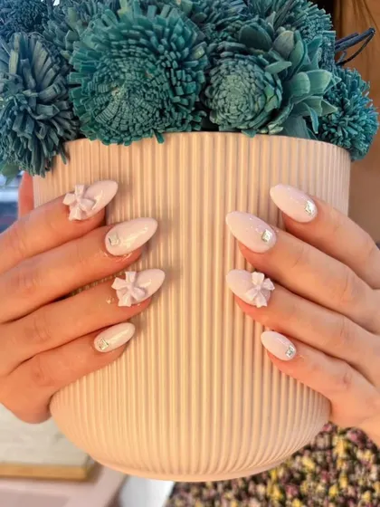 Soft and romantic. This almond-shaped set features a milky white base with delicate 3D bows and a touch of sparkle.
