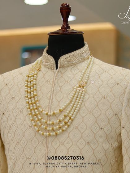 Quality and tradition never go out of style. This close-up highlights the rich texture of the fabric and the exquisite pearl necklace, a key accessory for a royal groom look.