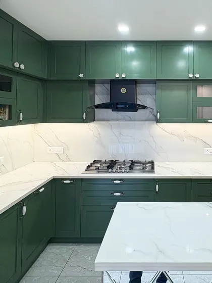 A stunning kitchen with dark olive green PU-painted cabinets, a white marble-patterned countertop and backsplash, and elegant hardware.