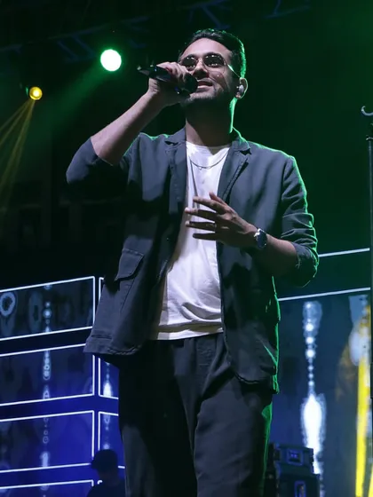 Sanam Puri, lead singer of the band Sanam, captivating the audience at a Sangeet night. We ensure the stage lighting and backdrop enhance the performance.