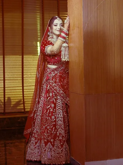A full-length portrait of the bride in her red lehenga, posed elegantly. This is a classic shot that highlights the entire bridal look.
