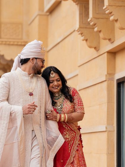 A quiet moment of connection between the couple, their outfits complementing the warm, golden tones of the Jaisalmer palace.