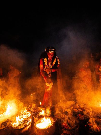 A devotee stands enveloped in smoke and fire, creating an ethereal and powerful scene that speaks to the spiritual intensity of the Kulasai Dasara.