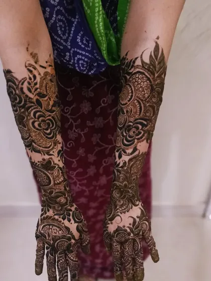 This full-arm design showcases a mix of Arabic floral patterns and Indian motifs. The contrast between the dark henna and the skin is what makes this style so eye-catching.
