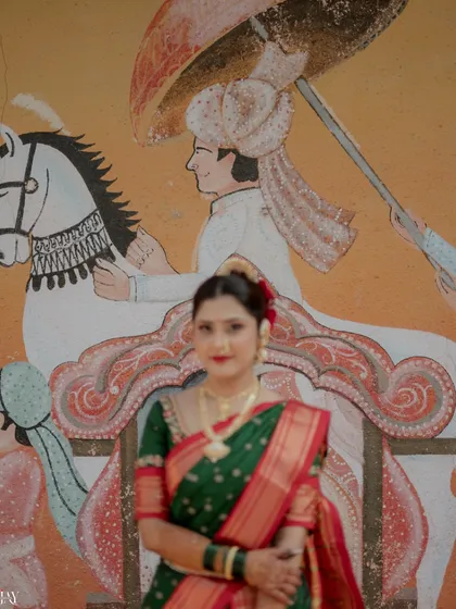 A portrait of the bride standing before a traditional mural, creating a beautiful blend of art and reality. Her confident pose and direct gaze make for a powerful and striking image.
