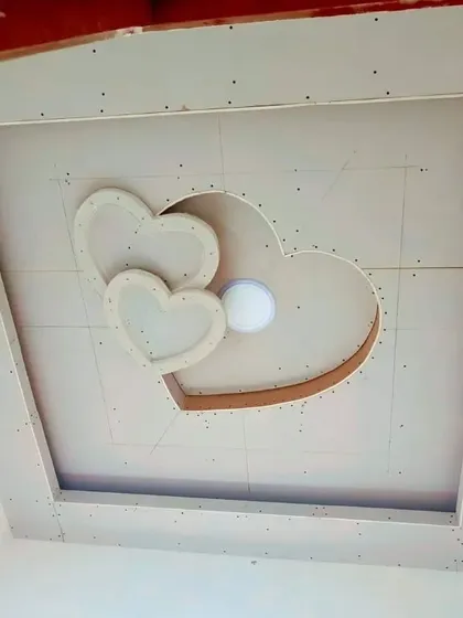 This image shows a heart-themed ceiling design under construction. The layered hearts create a 3D effect and include a central opening for a light fixture.