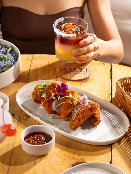 Crispy chicken wings paired with a cocktail. A classic bar food shot with a lifestyle element.