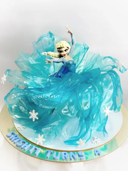 A dramatic Elsa cake设计, with the character's dress created from flowing, edible rice paper sails. This gives the cake a sense of movement and magic.