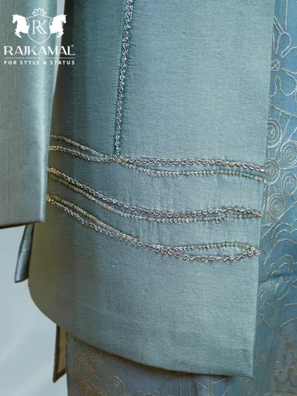A detail shot of the sleeve and side of the pastel green jacket, highlighting the delicate chain-stitch embroidery.