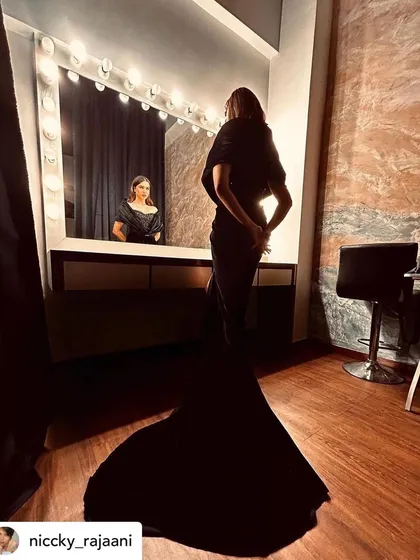 Another perspective from the dressing room, showing the complete look with the long train of the gown. The makeup stands out even from a distance, highlighting the importance of a well-executed glamorous look.