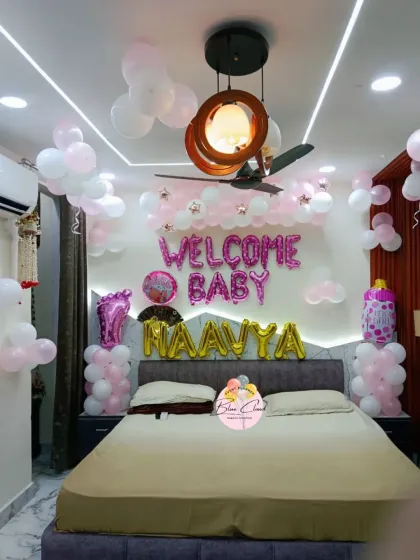 An elegant 'Welcome Baby' girl room decoration in pink and white. The setup includes balloon pillars, foil letters, and a personalized name.