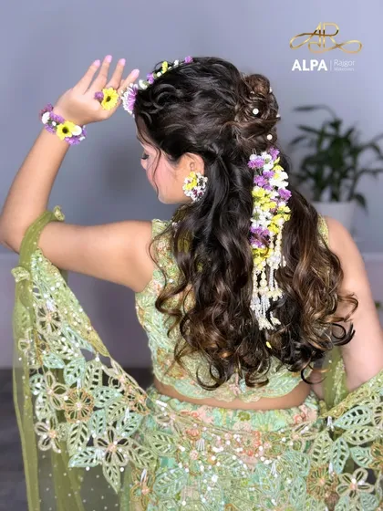 The complete look from the back, showing how the floral hairpiece cascades down the curly hair.
