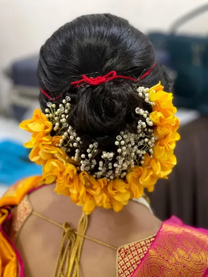 A beautiful floral bun for a Maharashtrian bride. The combination of yellow flowers and baby's breath creates a fresh and vibrant look that complements her saree.