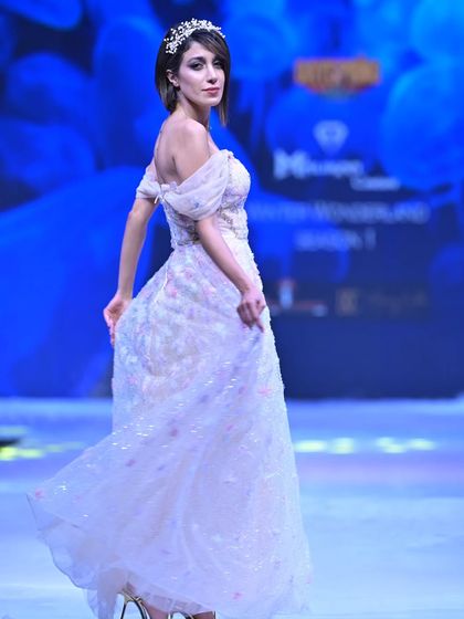 A moment of pure elegance on the runway. This off-shoulder gown from my GULFAM collection flows beautifully, its subtle shimmer creating an ethereal glow.