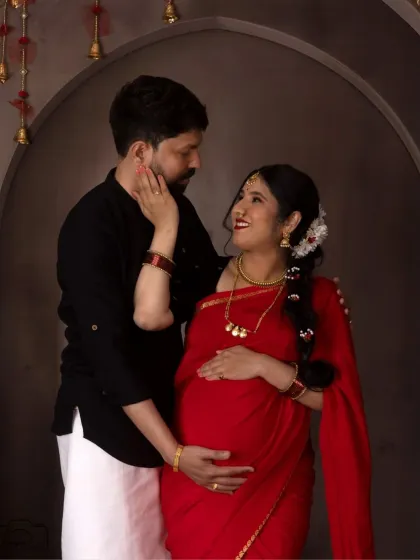 The loving gaze between this couple is beautifully captured. Their traditional outfits and the classic studio setup create a timeless and elegant image.