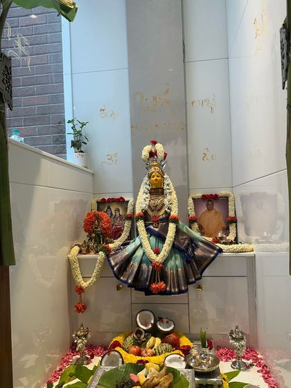 A beautifully decorated pooja space during a housewarming ceremony. The idols are adorned with flowers and offerings, filling the home with divine blessings.