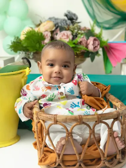 A happy baby in a handprint-patterned kurta. Our Holi mini sessions are safe and clean, using props and colorful backdrops to create a festive feel without the mess.