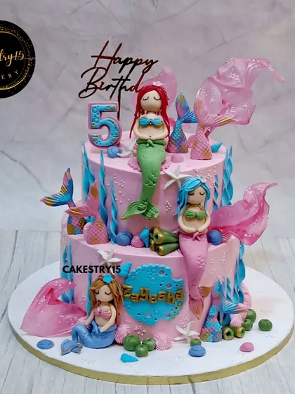 Dive into an underwater adventure with this vibrant two-tier mermaid cake. The cake is decorated with handcrafted fondant mermaids, colorful coral, and shimmering sugar work to create a magical oceanic scene.