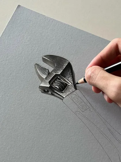 A close-up of the spanner drawing in progress. I'm using a black colored pencil to carefully render the intricate details of the tool's head.