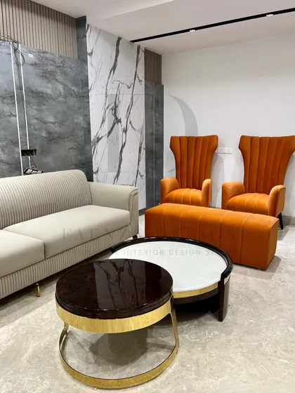 A complete living room set featuring a beige channel-tufted sofa and loveseat, paired with bold orange high-back chairs. The nesting coffee tables with marble tops complete this vibrant and modern look.