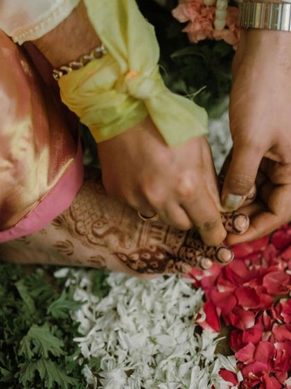 A candid shot from a wedding ceremony, showing a glimpse of the intricate foot mehendi during the rituals.