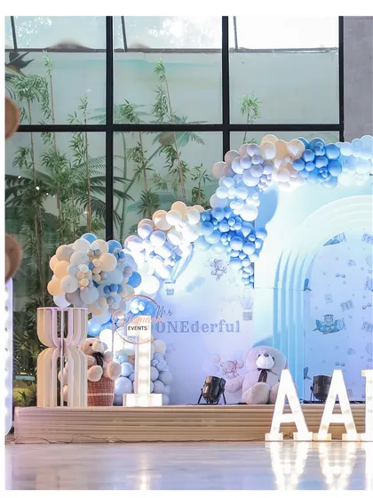 A side view of the blue teddy bear party stage, showing the depth created by the layered arches and balloon installations.