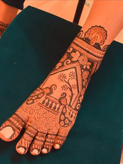 This foot design features a beautiful scene with two peacocks under a tree, framed by intricate borders.
