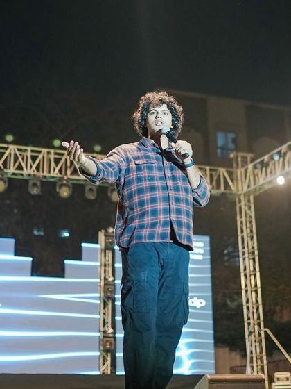 Joel D'souza interacting with the crowd in front of the branded 'Felicity' stage backdrop.