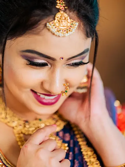 A tight close-up that focuses on the model's joyful expression and the fine details of her makeup and jewelry. This type of shot is essential for highlighting specific pieces like the nose ring and maang tikka for accessory brands.