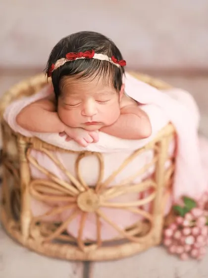 Wrapped in the sweetest shade of pink. This 'chin on hands' pose in a basket is a classic way to showcase a newborn's peaceful, sleeping face.